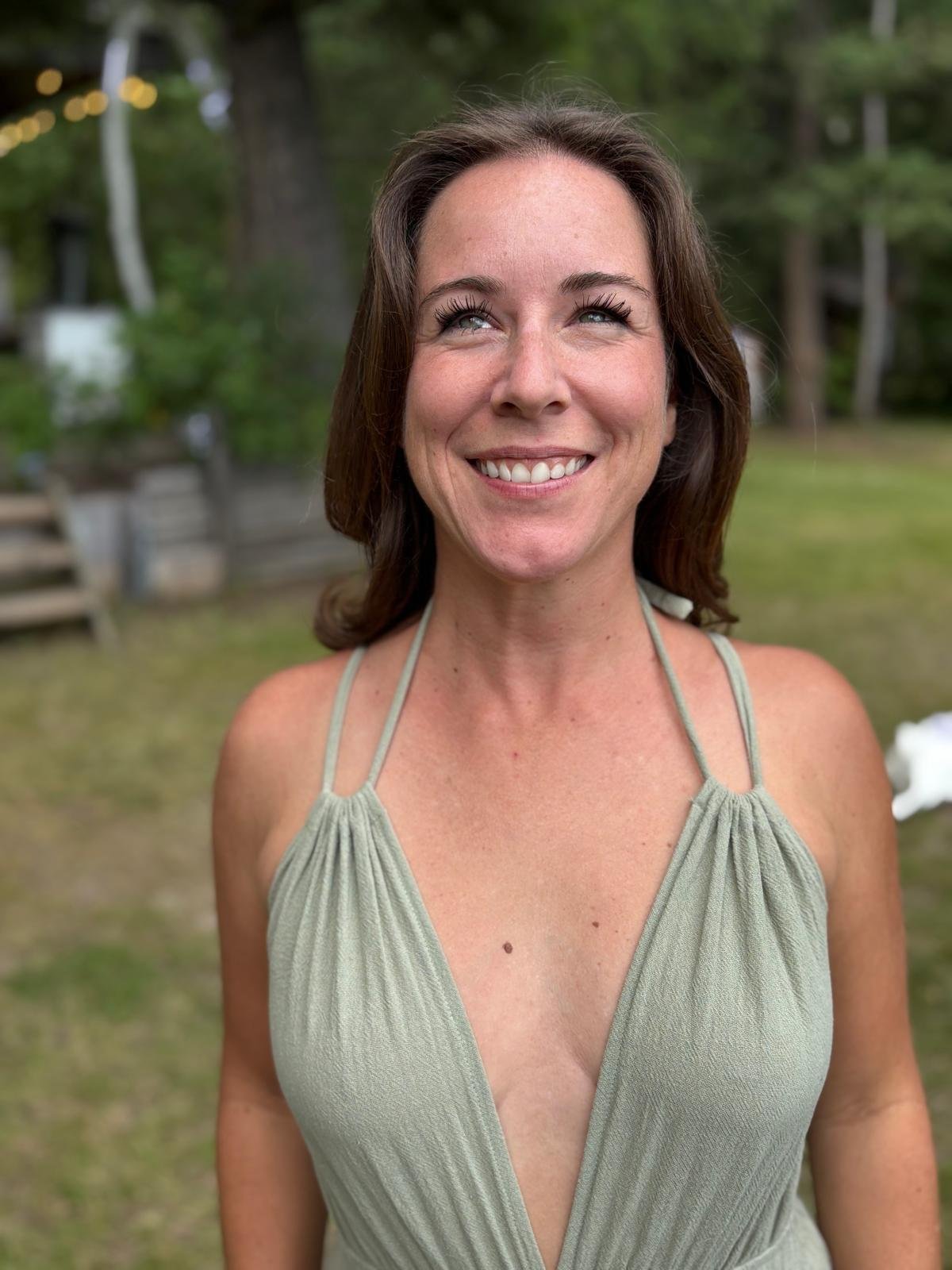 Jenna Jade smiling outdoors in a sage-green dress.